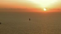 HD stock footage aerial video of the rising sun and a pair of oil platforms in the Gulf of Mexico Aerial Stock Footage | AF0001_000341