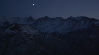 4K stock footage aerial video the moon over the snow covered Chugach Mountains at night, Alaska Aerial Stock Footage | AK0001_1121