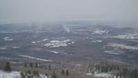 4K stock footage aerial video flying away from wooded slope revealing Anchorage, Alaska in snow Aerial Stock Footage | AK0001_1511