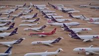 5K stock footage aerial video orbit rows of FedEx cargo planes at a desert boneyard at Victorville Airport, California at Sunset Aerial Stock Footage | AX0007_007E