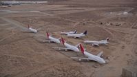 5K stock footage aerial video orbit seven airliners parked at aircraft boneyard in Sunset, Victorville Airport, California Aerial Stock Footage | AX0007_013