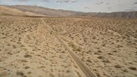 5K stock footage aerial video approach and fly over a silver sedan on a lonely desert road in Joshua Tree National Park, California Aerial Stock Footage | AX0011_007