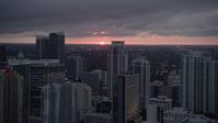 5K stock footage aerial video of the setting sun low on the horizon beyond Downtown Miami skyscrapers, Florida Aerial Stock Footage | AX0022_088E