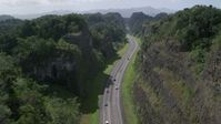 4.8K stock footage aerial video of Light traffic on a highway through lush green mountains, Karst Forest, Puerto Rico Aerial Stock Footage | AX101_084