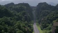 4.8K stock footage aerial video Flying above highway cutting through lush green mountains, Karst Forest, Puerto Rico Aerial Stock Footage | AX101_085