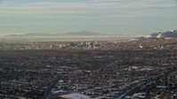 5.5K stock footage aerial video of a view of Downtown Salt Lake City across suburban neighborhoods in winter at sunset, Utah Aerial Stock Footage | AX127_075