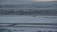 5.5K stock footage aerial video orbit airport runway as airliner lifts off in background at sunset with winter snow, Salt Lake City, Utah Aerial Stock Footage | AX127_171
