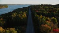 5.5K stock footage aerial video flying over quiet road among a colorful forest in autumn, Stockton Springs, Maine, sunset Aerial Stock Footage | AX149_120