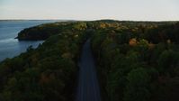 5.5K stock footage aerial video flying over a road situated among, colorful forest in autumn, Stockton Springs, Maine, sunset Aerial Stock Footage | AX149_122