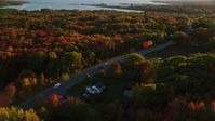 5.5K stock footage aerial video tracking car on road passing through small town, and trees, autumn, Stockton Springs, Maine, sunset Aerial Stock Footage | AX149_145