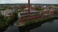 5.5K stock footage aerial video flying by riverside abandoned factory and smoke stack, autumn, Lowell, Massachusetts Aerial Stock Footage | AX152_129