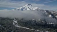 5.5K stock footage aerial video of low clouds over forest and ridge near snow-capped Mount Hood, Cascade Range, Oregon Aerial Stock Footage | AX154_121