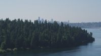 5K stock footage aerial video of Downtown Seattle skyline in the far distance beyond the tree-covered Bailey Peninsula, Washington Aerial Stock Footage | AX47_007