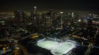 5K stock footage aerial video fly over high school sports fields to approach Downtown Los Angeles skyscrapers, California, night Aerial Stock Footage | AX64_0356