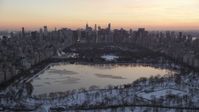 4.8K stock footage aerial video of Central Park lake and Midtown Manhattan skyline in winter, New York City, twilight Aerial Stock Footage | AX66_0297