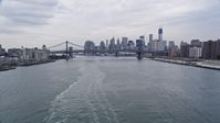 4K stock footage aerial video tilt from ferry on the East River, and approach Manhattan and Brooklyn Bridge, Lower Manhattan skyline, New York City Aerial Stock Footage | AX84_101E