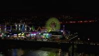HD stock footage aerial video of a reverse view of the Ferris wheel and rides at nighttime, Santa Monica Pier, California Aerial Stock Footage | CAP_018_124