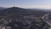 HD stock footage aerial video of reverse view of Universal Studios Hollywood theme park, reveal downtown skyline, Universal City, California Aerial Stock Footage | CAP_021_125