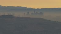 HD stock footage aerial video of a smoggy skyline beyond hills, Downtown Los Angeles, California, sunset Aerial Stock Footage | CBAX01_065