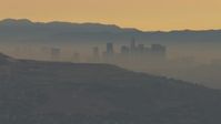 HD stock footage aerial video of a smoggy skyline beyond hills, Downtown Los Angeles, California, sunset Aerial Stock Footage | CBAX01_067
