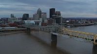 5.7K stock footage aerial video ascend by bridge spanning river at sunset for view of skyline, Downtown Louisville, Kentucky Aerial Stock Footage | DX0001_003074