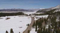 5.7K stock footage aerial video pass and follow a country road in snowy valley with view of mountains, New Mexico Aerial Stock Footage | DX0002_134_018