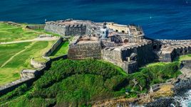 A historic fort and lighthouse beside blue waters, Old San Juan, Puerto Rico Aerial Stock Photos | AX101_026.0000000F