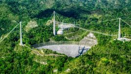 Wide shot of the Arecibo Observatory among lush green forests, Puerto Rico  Aerial Stock Photos | AX101_090.0000276F