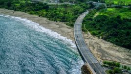 Coastal road cutting through trees and over a beach by blue water, Arecibo, Puerto Rico  Aerial Stock Photos | AX101_140.0000000F