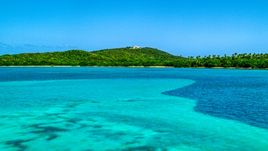 A view across crystal clear blue water of Cape San Juan Light, Puerto Rico Aerial Stock Photos | AX102_060.0000000F