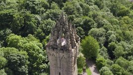 The top of historic Wallace Monument among trees, Stirling, Scotland Aerial Stock Photos | AX109_052.0000016F