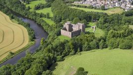 The iconic Doune Castle with trees along a river, Scotland Aerial Stock Photos | AX109_074.0000000F