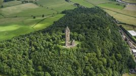 The historic Wallace Monument surrounded by trees on Abbey Craig hill in Stirling, Scotland Aerial Stock Photos | AX109_100.0000008F