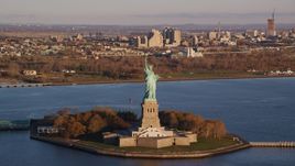 Statue of Liberty at sunrise in New York, with Jersey City in the background Aerial Stock Photos | AX118_144.0000175F
