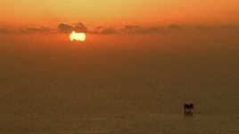 HD aerial stock footage of the sun rising behind clouds over an oil platform in the Gulf of Mexico Aerial Stock Footage | AF0001_000339