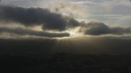 8K aerial stock footage of godrays shining from behind clouds onto homes in Southern California at sunset Aerial Stock Footage | AF0001_001029