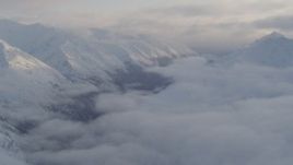 4K aerial stock footage valley between snow covered peaks, low clouds, Chugach National Forest, Alaska Aerial Stock Footage | AK0001_0012