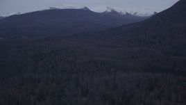 4K aerial stock footage descending over forested hills, approaching Chugach Mountains, Alaska, twilight Aerial Stock Footage | AK0001_0185