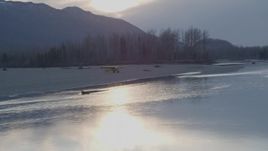 4K aerial stock footage flying low by a small plane on the shore of the river, Knik River, Alaska, sunset Aerial Stock Footage | AK0001_0310