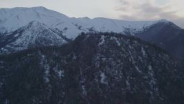 4K aerial stock footage fly over wooded summit, approaching snowy Chugach Mountains, Alaska, twilight Aerial Stock Footage | AK0001_0319