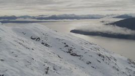 4K aerial stock footage flying along snowy slope, reveal low clouds over bay, Prince William Sound, Alaska Aerial Stock Footage | AK0001_0420