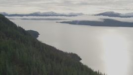 4K aerial stock footage rounding a forested mountain peak toward a bay, Prince William Sound, Alaska Aerial Stock Footage | AK0001_0427
