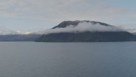 4K aerial stock footage fly by forested cloud covered peak, from over bay, Prince William Sound, Alaska Aerial Stock Footage | AK0001_0430