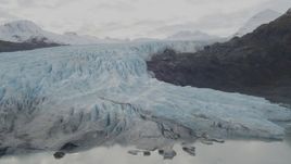 4K aerial stock footage fly by a glacier spilling over ridge into lake, Prince William Sound, Alaska Aerial Stock Footage | AK0001_0448