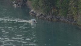 4K aerial stock footage track a boat, near tree lined shore of the bay, Prince William Sound, Alaska Aerial Stock Footage | AK0001_0457