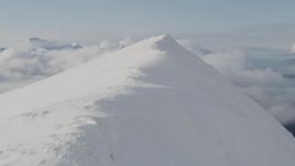 4K aerial stock footage flying over snowy summit, revealing thick clouds, Kenai Mountains, Alaska Aerial Stock Footage | AK0001_0530