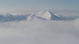4K aerial stock footage flying by snow covered Kenai Mountains, low clouds, Kenai Mountains, Alaska Aerial Stock Footage | AK0001_0535