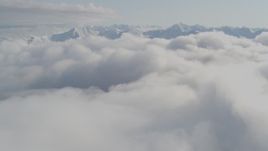 4K aerial stock footage flying over low clouds, by snow capped peaks, Kenai Mountains, Alaska Aerial Stock Footage | AK0001_0536