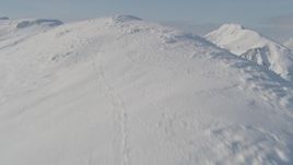 4K aerial stock footage flying up snowy slope, reveal mountain range below, Kenai Mountains, Alaska Aerial Stock Footage | AK0001_0540