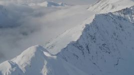 4K aerial stock footage descending a snowy ridge, approaching low clouds, Kenai Mountains, Alaska Aerial Stock Footage | AK0001_0541